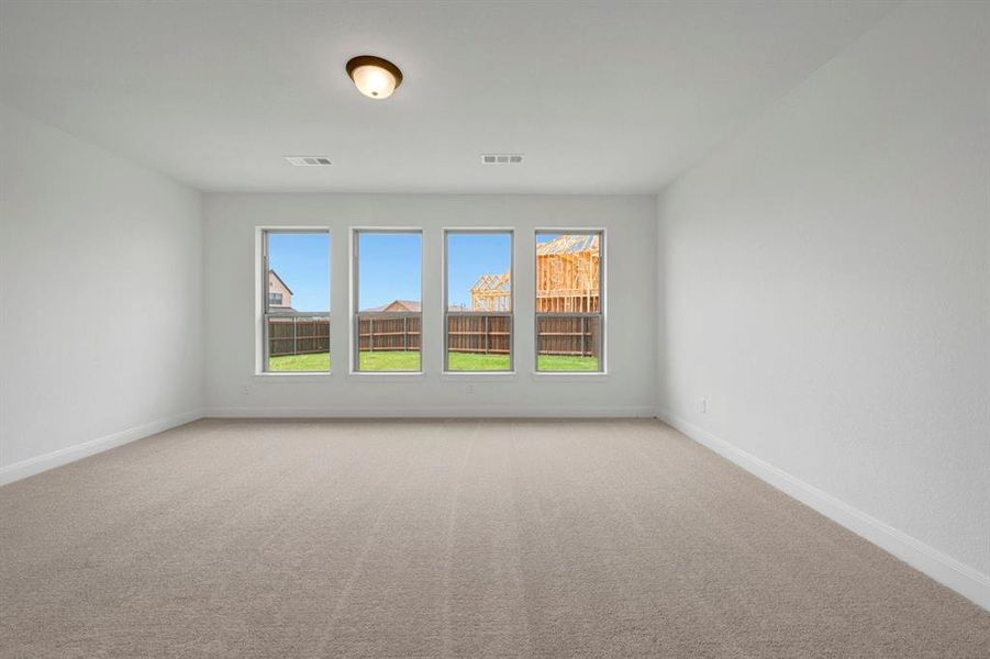 Spacious room featuring four large windows, neutral carpet flooring, white walls, and a ceiling-mounted light fixture
