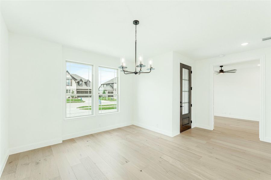 Dining room with light hardwood floors, black chandelier, and glass-paned door
