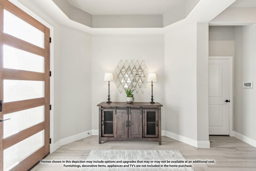 Entryway with wood and glass front door, tray ceiling, and rustic console table with two lamps