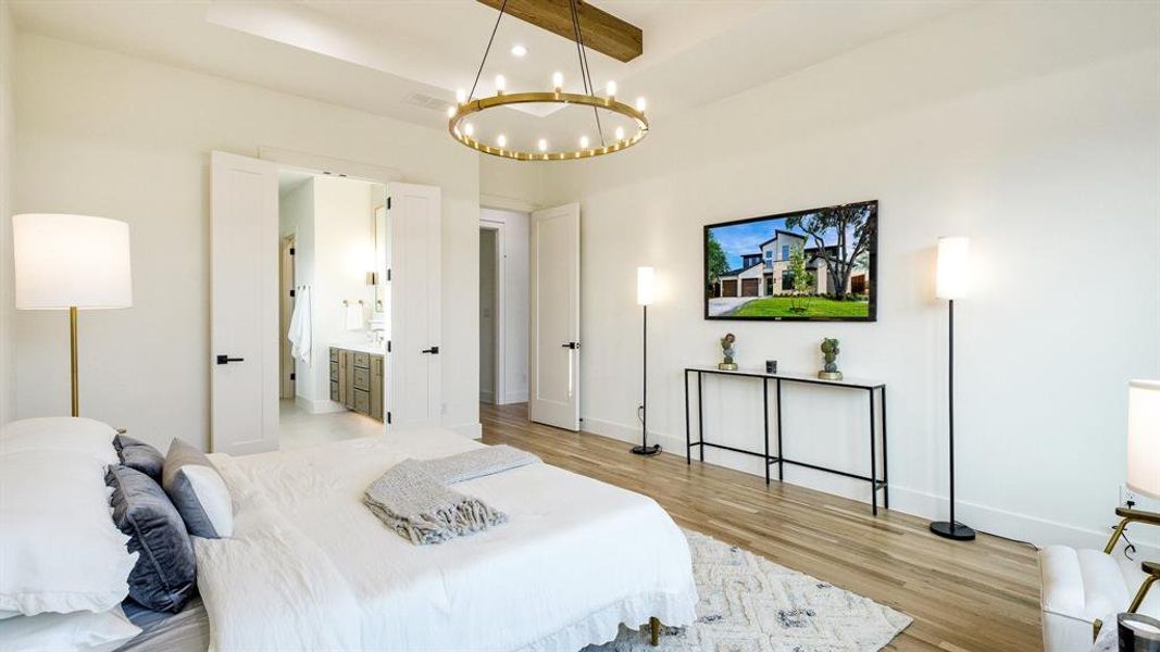 Bedroom with light hardwood / wood-style flooring, connected bathroom, a notable chandelier, and beam ceiling