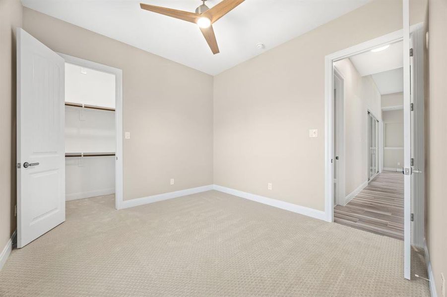 bedroom with ceiling fan, a walk in closet, a closet, and light carpet