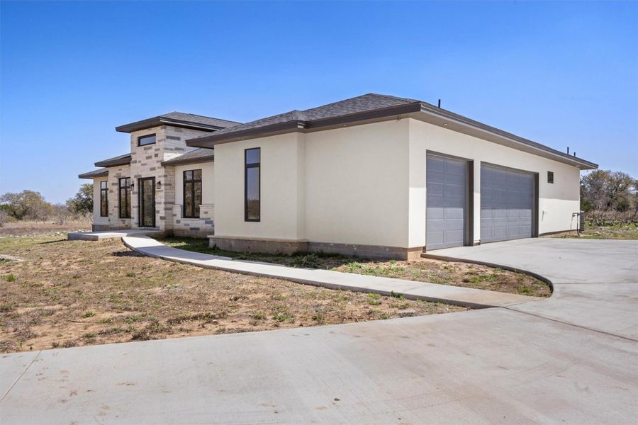 View of front of property featuring stucco siding, concrete driveway, and an attached garage