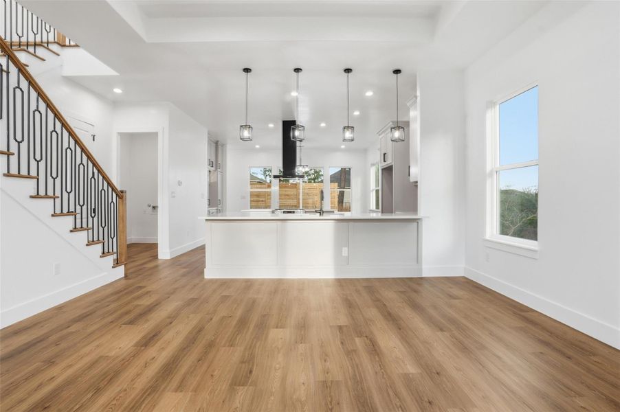 Kitchen with light countertops, a peninsula, pendant lighting, and light wood-style floors
