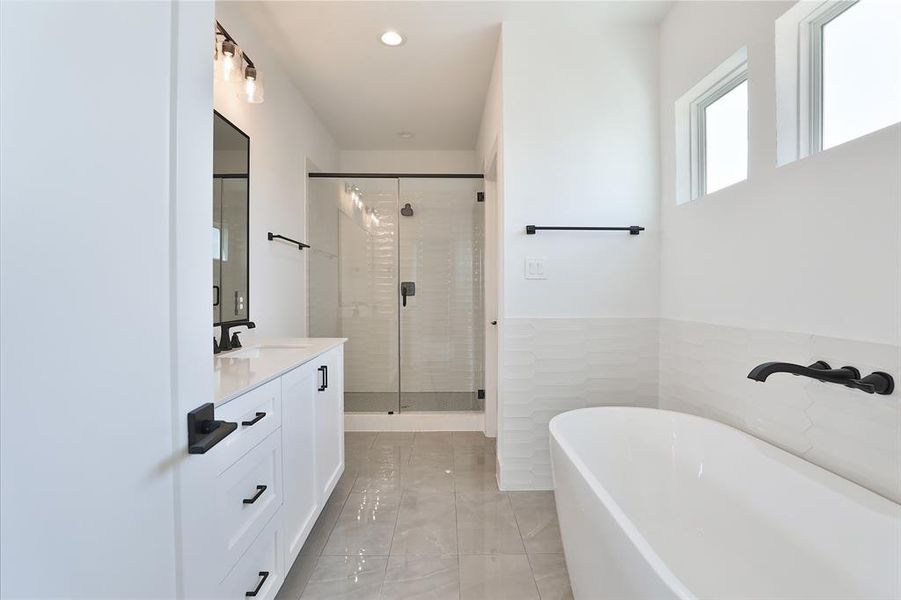 A luxurious primary bath suite featuring a spacious walk-in shower with matte gray hexagon mosaic floor tiles.