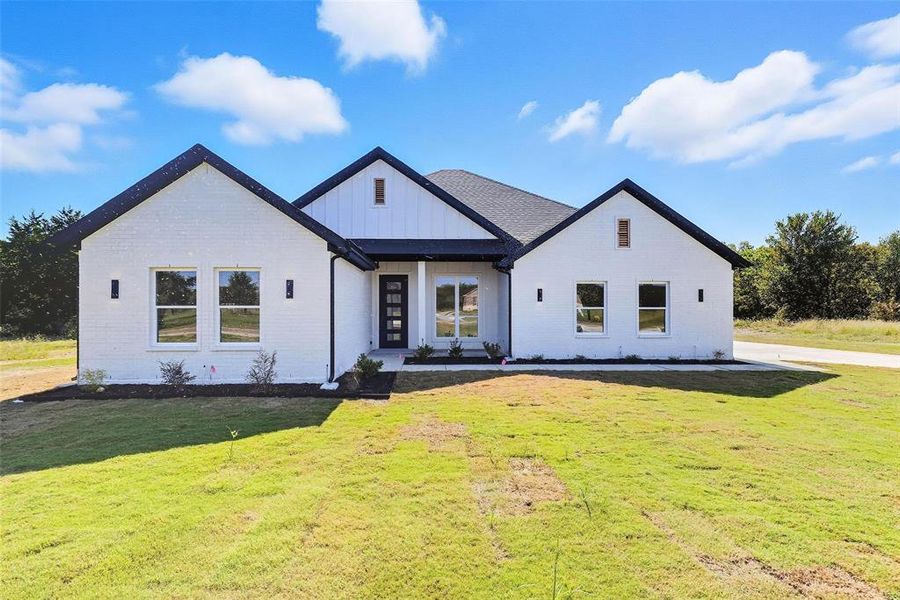 Modern farmhouse featuring board and batten siding, brick siding, and a front lawn Modern farmhouse featuring board and batten siding, brick siding, and a front lawn