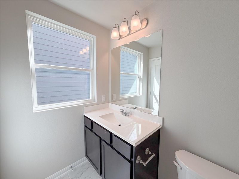 Bathroom featuring a dark wood-finish vanity with a white countertop and integrated sink, a large mirror, and a three-light vanity fixture