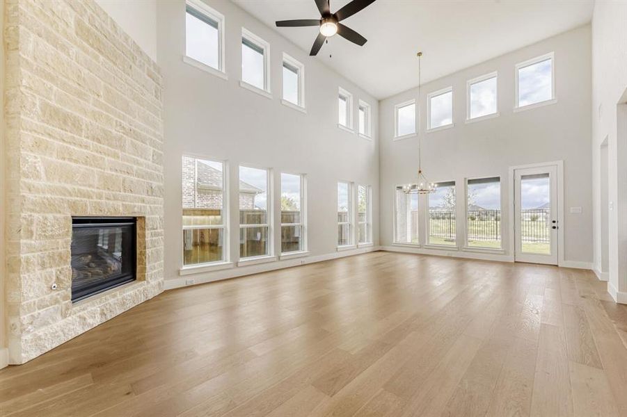 Unfurnished living room with light wood-type flooring, a fireplace, healthy amount of natural light, and a high ceiling