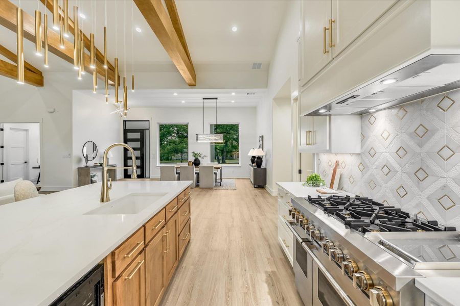 Kitchen featuring two tone cabinetry, range with two ovens, beamed ceiling, light wood-style flooring, and pendant lighting