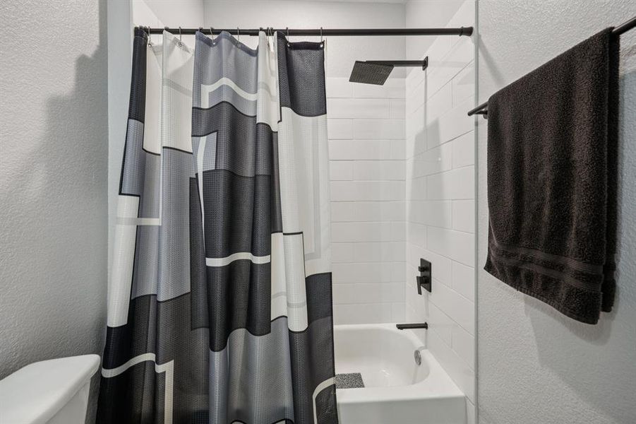 Full bathroom featuring a textured wall and shower / tub combo Full bathroom featuring a textured wall and shower / tub combo