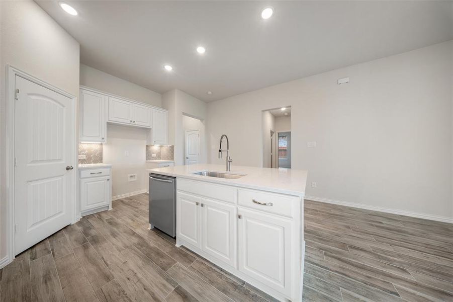 Kitchen with light wood finished floors, light countertops, white cabinetry, and recessed lighting