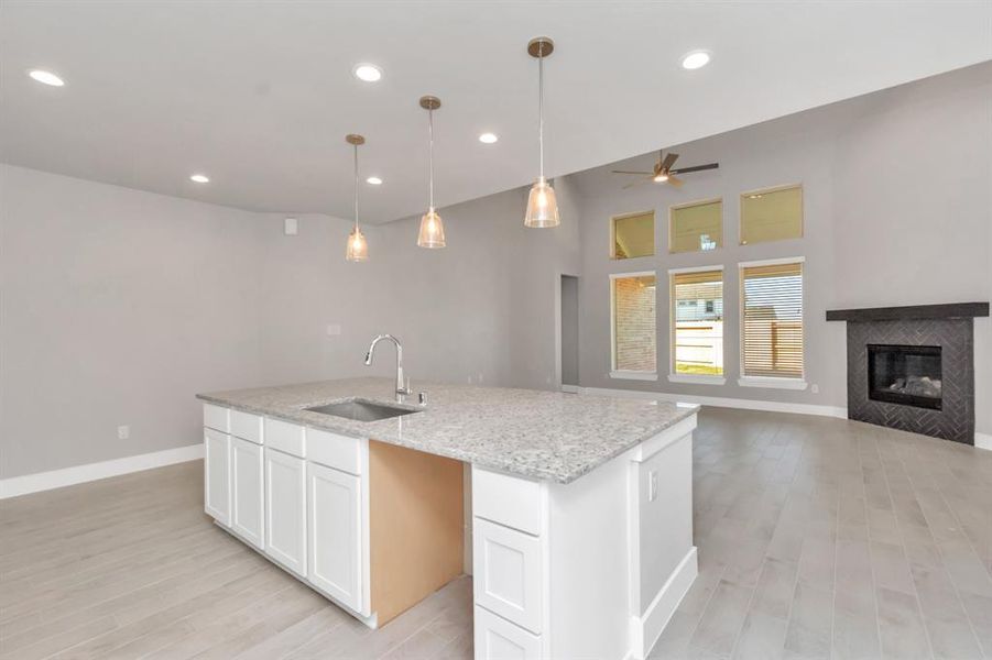 Kitchen opens up to the expansive family room, creating a perfect hub for gatherings. Sample photo of completed home with similar floor plan. As-built interior colors and selections may vary.