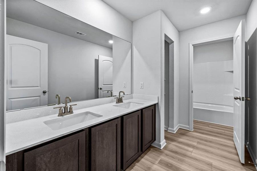 Bathroom with shower / tub combination, double vanity, and hardwood / wood-style floors