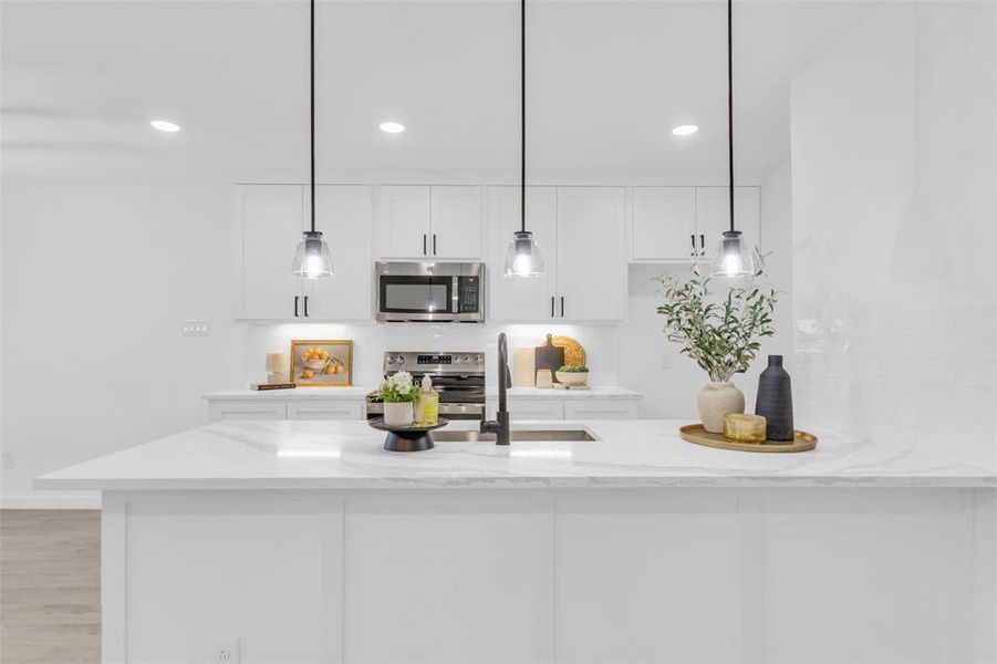 Kitchen featuring appliances with stainless steel finishes, white cabinetry, light stone countertops, pendant lighting, and recessed lighting