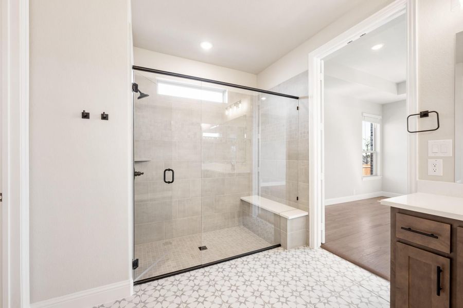 Bathroom with glass-enclosed walk-in shower, built-in bench, tile walls, and wood vanity cabinet with white countertop