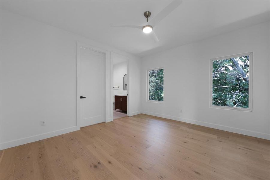 Unfurnished bedroom with light wood-style flooring, connected bathroom, and ceiling fan