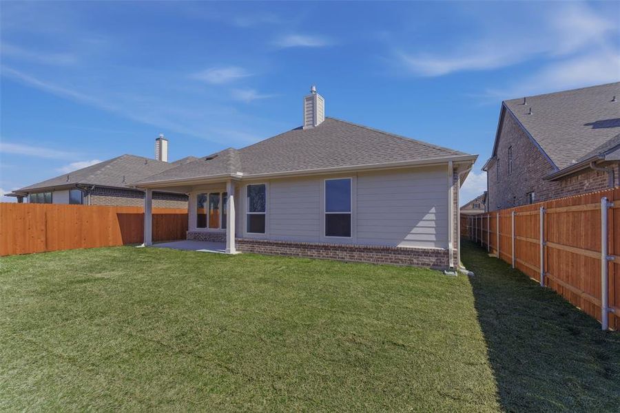 Rear view of property featuring a patio area, a fenced backyard, brick siding, and a chimney
