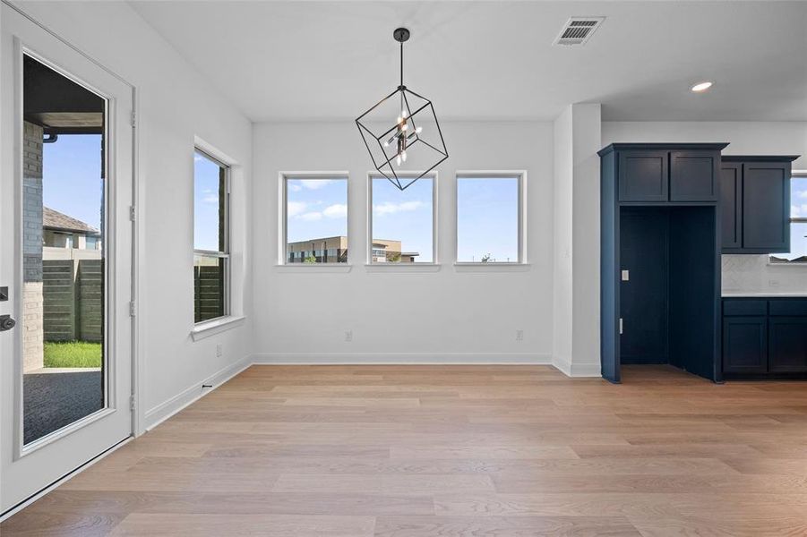 Unfurnished dining area featuring a wealth of natural light, light hardwood / wood-style flooring, and a chandelier