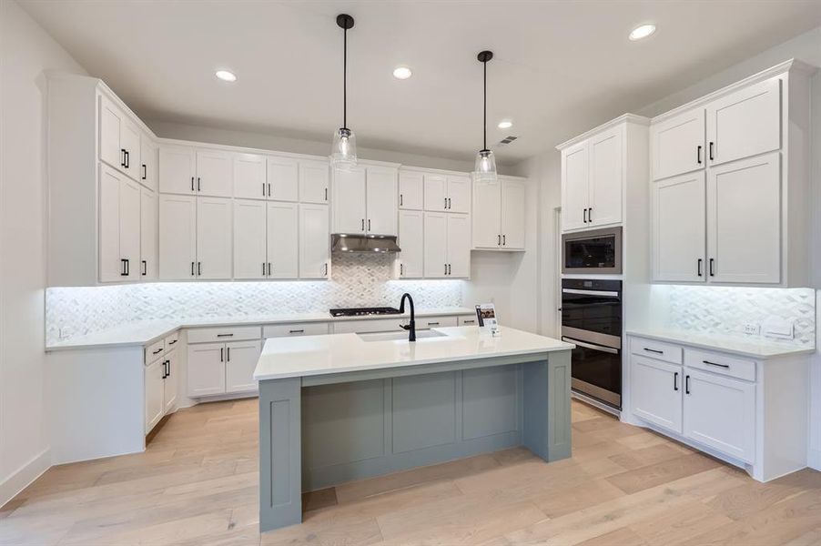 Kitchen with pendant lighting, light wood-type flooring, and white cabinets