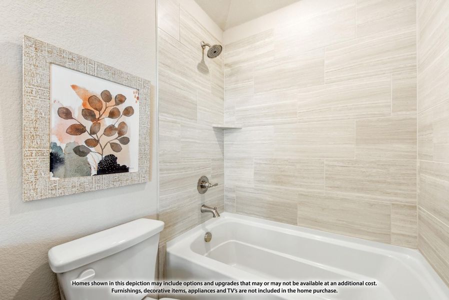 Bathroom with white soaking tub, tiled shower surround, and framed wall art beside toilet Bathroom with white soaking tub, tiled shower surround, and framed wall art beside toilet