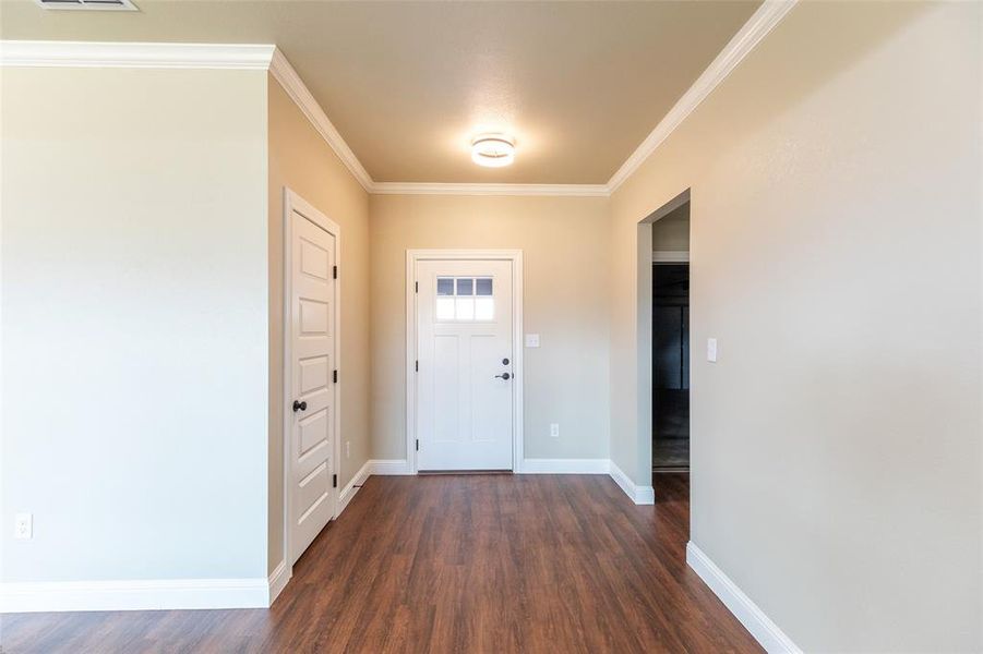 Entryway featuring wood-finish flooring, white crown molding, and a white paneled door with glass inserts