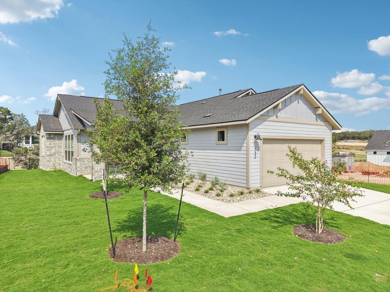 View of front facade with board and batten siding, a shingled roof, driveway, and stone siding
