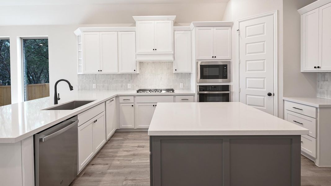 Kitchen with white cabinetry, backsplash, a kitchen island, and appliances with stainless steel finishes
