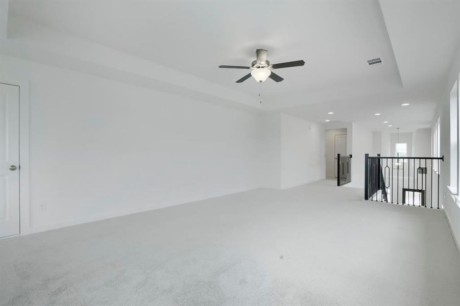 Expansive loft featuring plush carpet flooring, a contemporary ceiling fan, recessed lighting, and a black wrought iron railing overlooking the space below