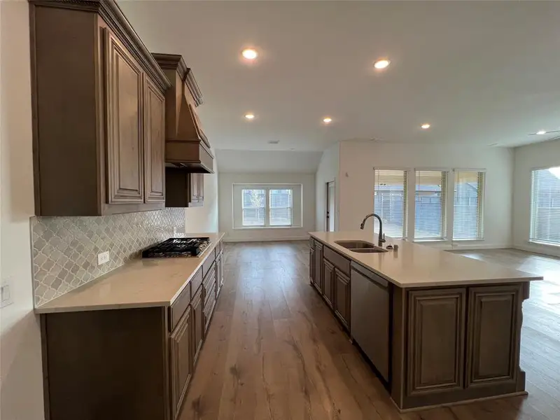 Kitchen with Charleston cabinetry, Arabesque tile backsplash, a center island with dual sink, quartz countertops, recessed lighting, stainless steel dishwasher, gas cooktop, and dark wood-type flooring Kitchen with Charleston cabinetry, Arabesque tile backsplash, a center island with dual sink, quartz countertops, recessed lighting, stainless steel dishwasher, gas cooktop, and dark wood-type flooring