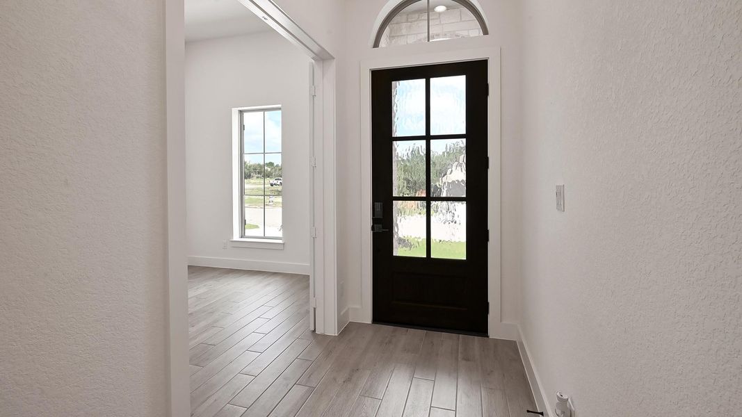 Entryway with a textured wall and light wood-type flooring Entryway with a textured wall and light wood-type flooring
