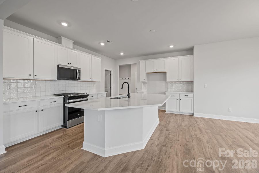 Large island with quartz countertops, gas range, open to the family and casual dining area.