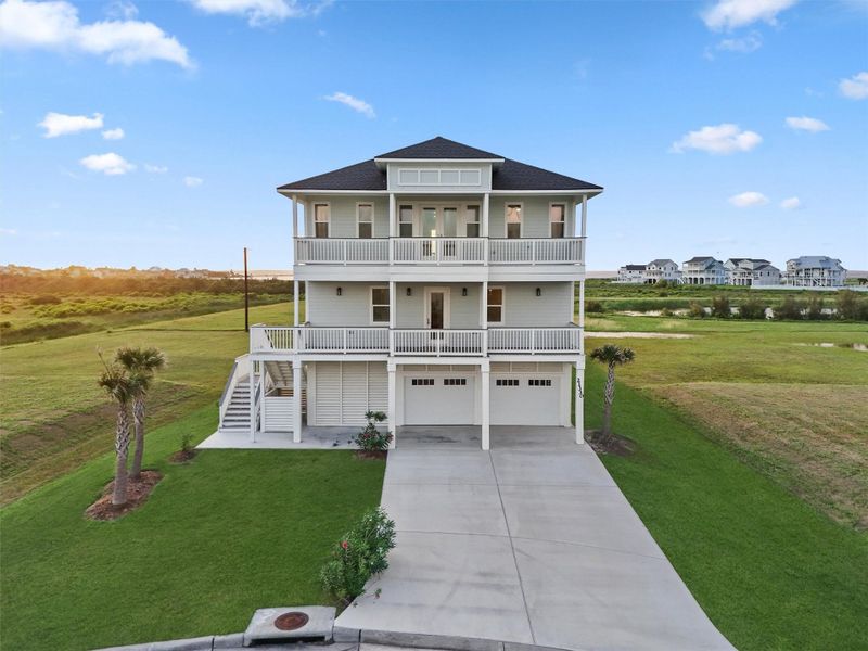 Classic symmetry and coastal style—this elevated home features storm-rated construction, breakaway walls, and wide driveway for guest parking. Classic symmetry and coastal style—this elevated home features storm-rated construction, breakaway walls, and wide driveway for guest parking.