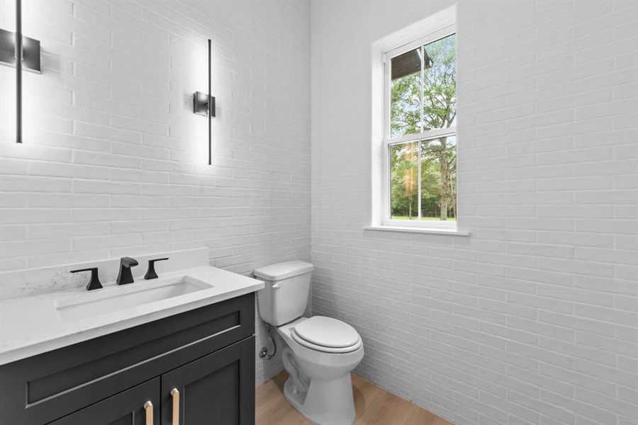 Downstairs half bath with brick wall detail, tucked behind kitchen and just off laundry room.