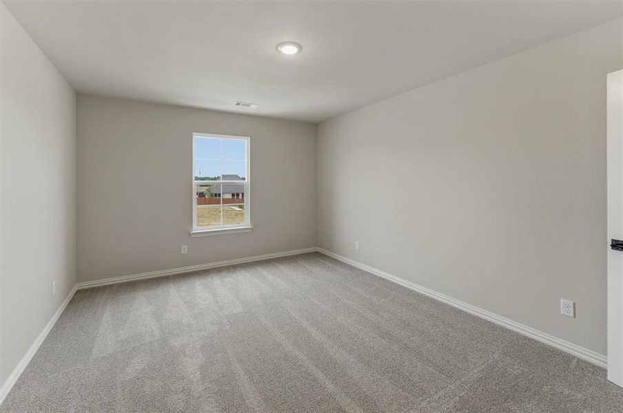 Neutral-toned interior room featuring light gray walls, gray carpet flooring, white baseboards, and a single window with white trim