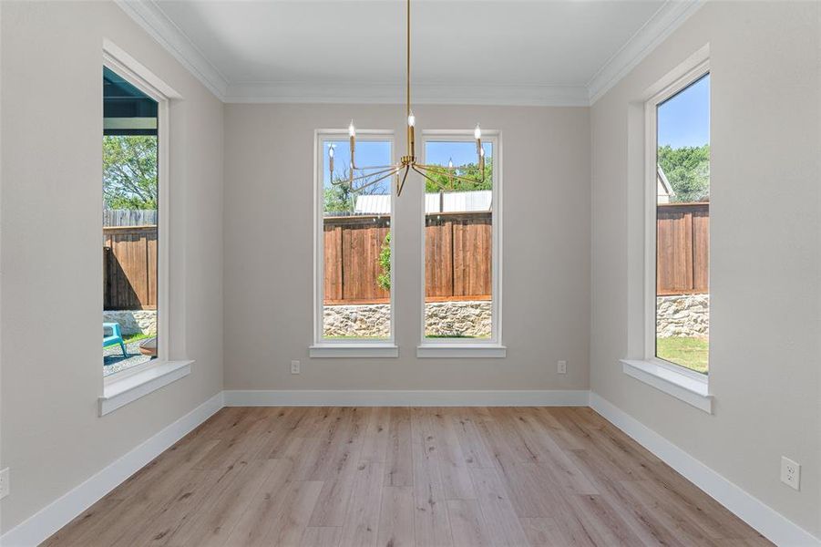 Unfurnished dining area with an inviting chandelier, light wood-type flooring, and ornamental molding