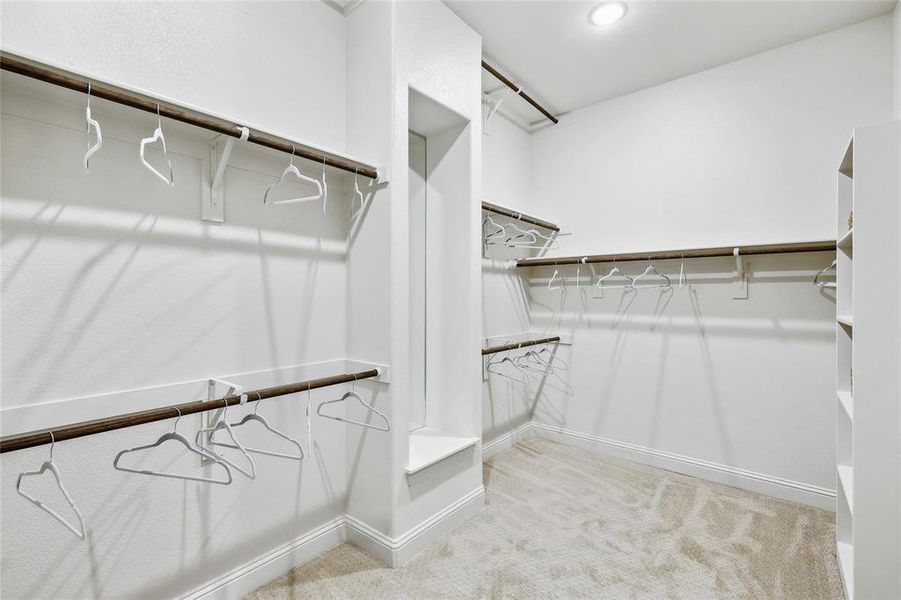 Spacious walk-in closet featuring multiple hanging rods, integrated shelving, and recessed lighting
