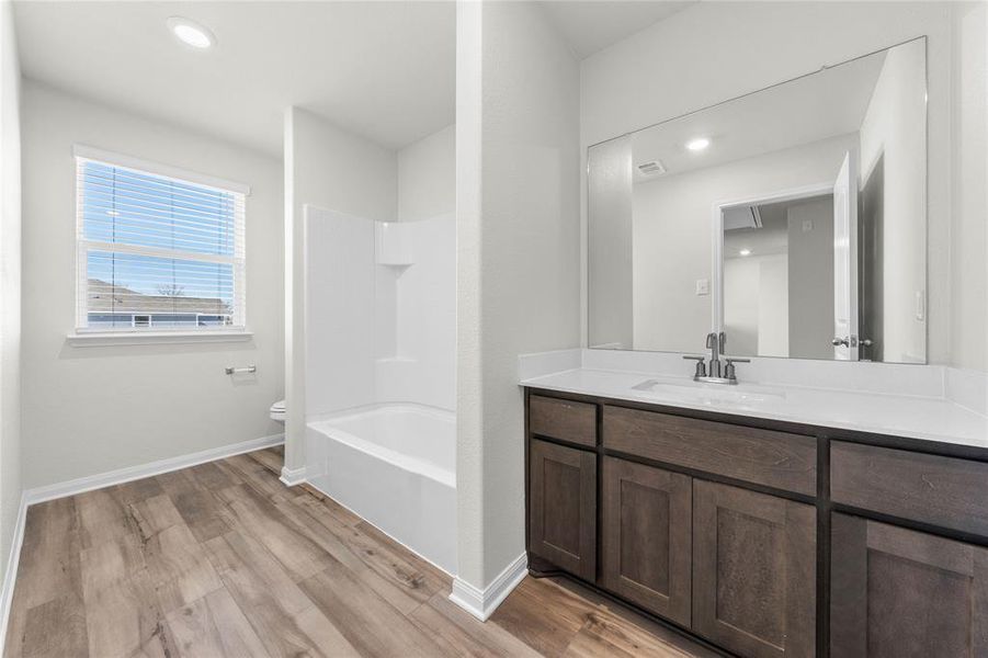 Full bathroom with vanity, wood finished floors, toilet, and baseboards