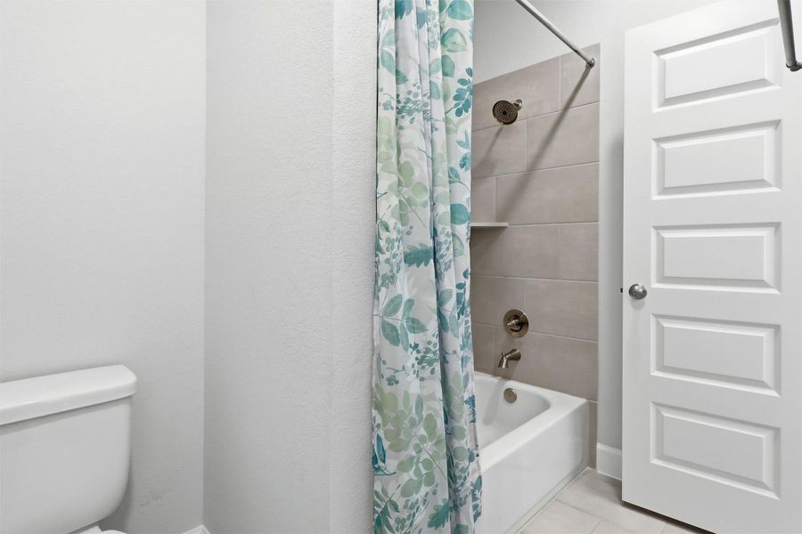 The upstairs jack-and-jill bathroom features timeless finishes, a tiled tub/shower combination, and a functional layout designed to comfortably serve family members and guests alike.