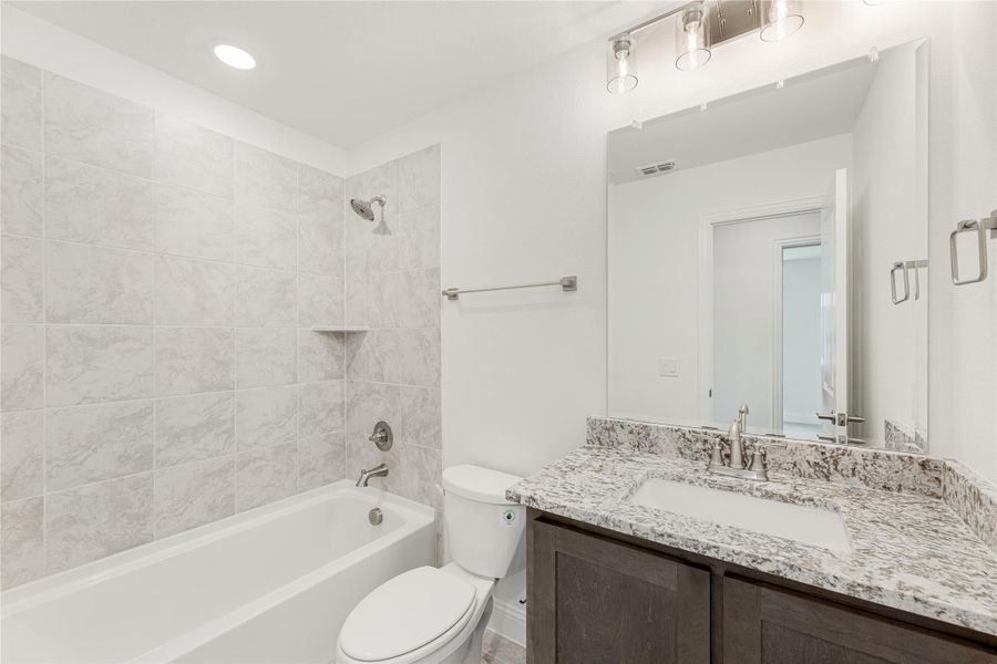 Bathroom with tiled tub-shower combo, granite countertop vanity, and dark wood cabinets Bathroom with tiled tub-shower combo, granite countertop vanity, and dark wood cabinets