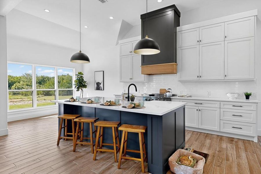 Kitchen featuring backsplash, light wood-type flooring, a kitchen breakfast bar, a center island with sink, and recessed lighting