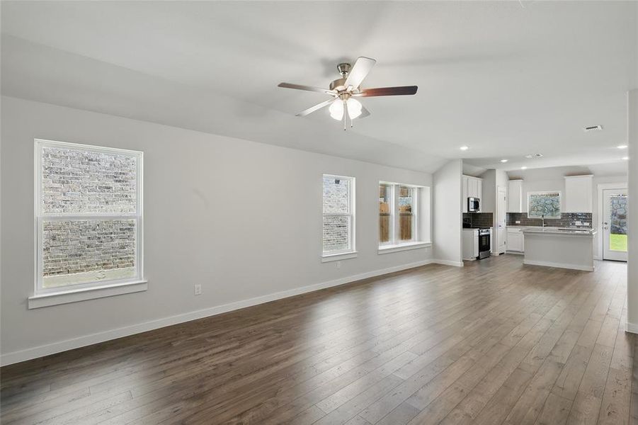 Unfurnished living room with a ceiling fan, recessed lighting, dark wood finished floors, and lofted ceiling Unfurnished living room with a ceiling fan, recessed lighting, dark wood finished floors, and lofted ceiling
