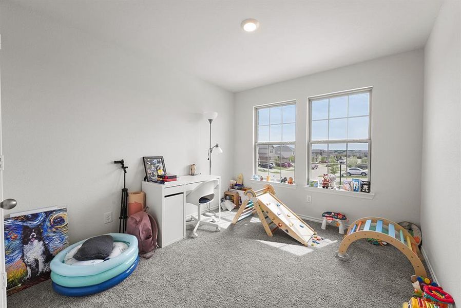 Bright room featuring two large windows with grid patterns, light gray carpet flooring, a built-in overhead light fixture, and neutral white walls