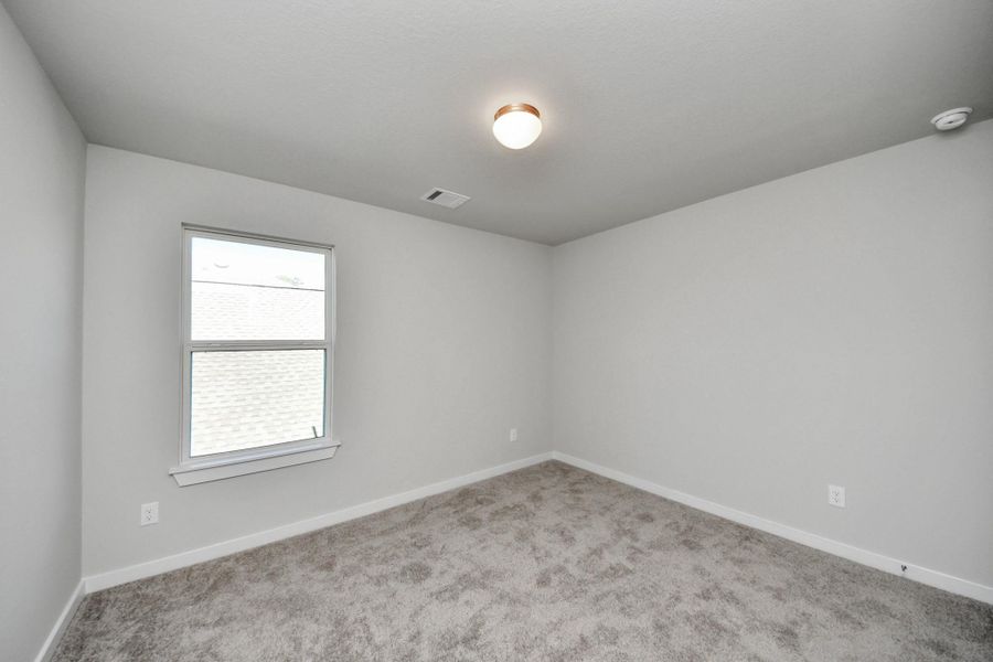 Secondary bedroom features plush carpeting, large windows that let in plenty of natural light, bright paint, and spacious closets. Sample photo of completed home with similar floor plan. Actual colors and selections may vary.