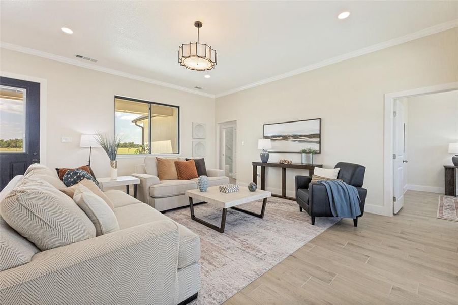 Spacious living area featuring light-toned walls, wood-finish flooring, recessed lighting, a decorative chandelier, and a large window