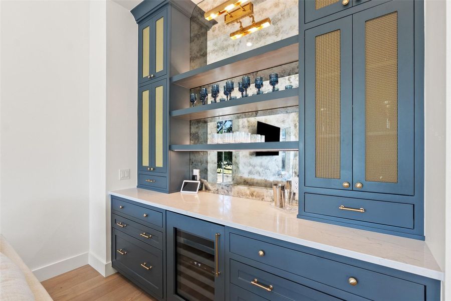 Custom cabinetry with a mirrored backsplash and under-shelf lighting creates a refined and functional beverage bar. Custom cabinetry with a mirrored backsplash and under-shelf lighting creates a refined and functional beverage bar.