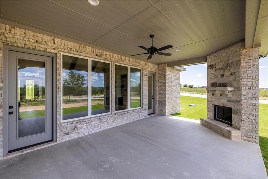 View of patio featuring an outdoor stone fireplace and ceiling fan