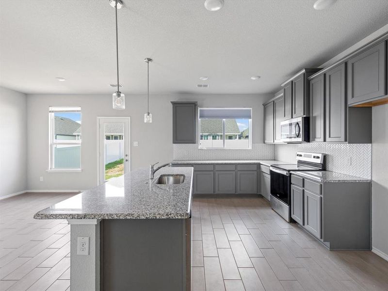 Kitchen featuring stainless steel appliances, wood finish floors, decorative backsplash, light stone countertops, and recessed lighting Kitchen featuring stainless steel appliances, wood finish floors, decorative backsplash, light stone countertops, and recessed lighting