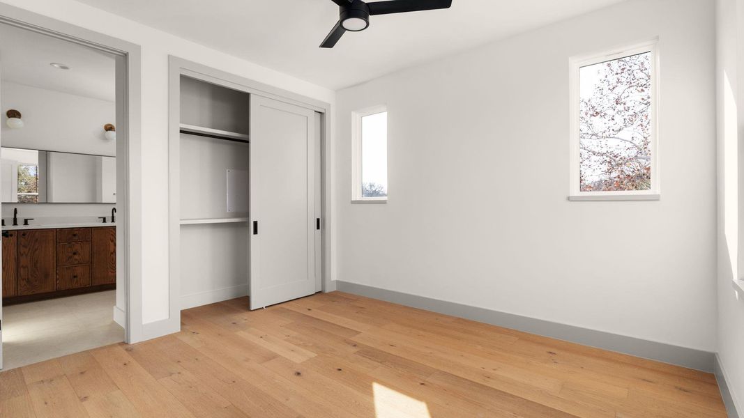 Unfurnished bedroom with multiple windows, light wood-style flooring, and a closet