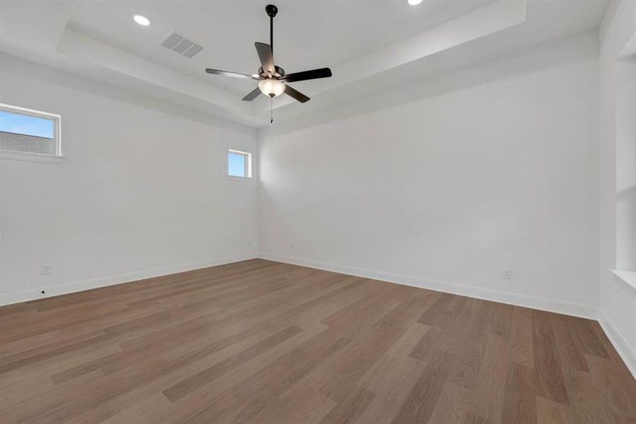 Spare room with dark wood-style flooring, ceiling fan, a tray ceiling, and recessed lighting