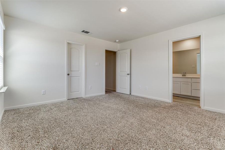 Unfurnished bedroom with sink, light carpet, and connected bathroom