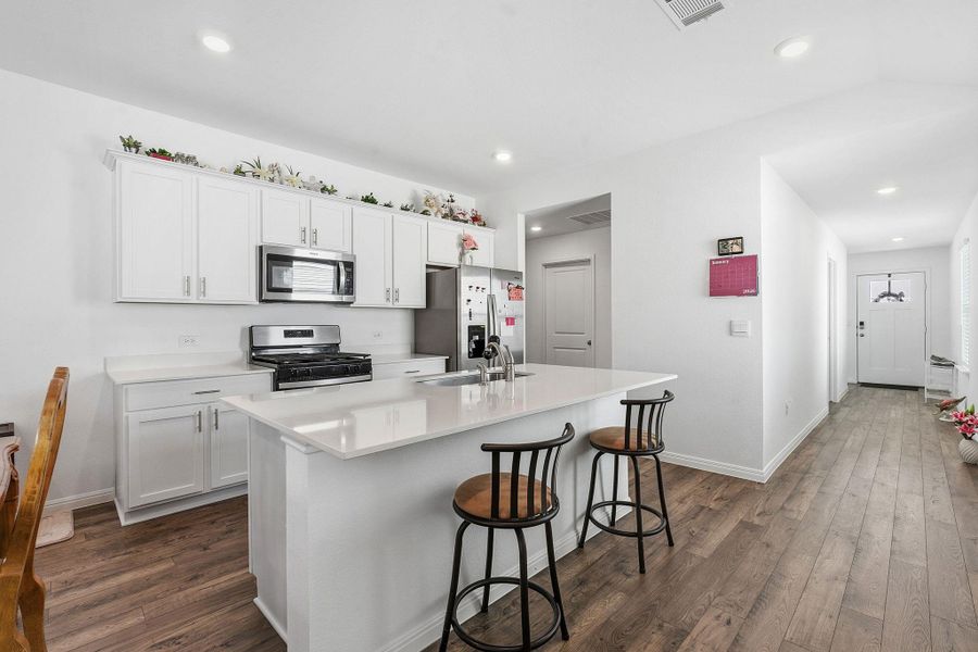 Kitchen with white cabinets, stainless steel appliances, a kitchen island with sink, dark wood-style flooring, and recessed lighting